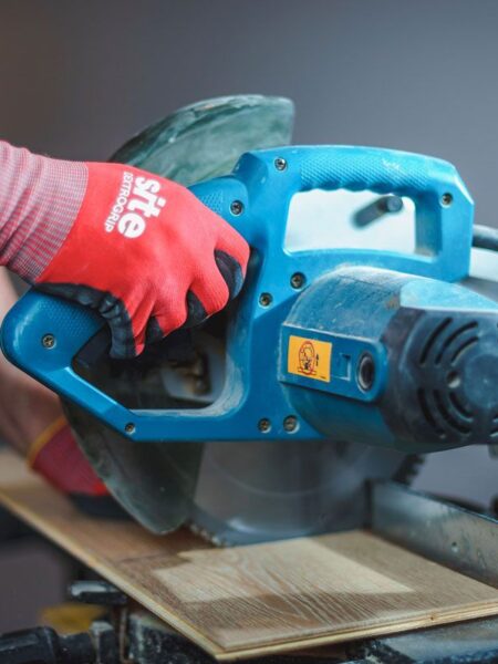 Professional floor layer precisely cutting oak parquet boards with a power saw for a custom installation.