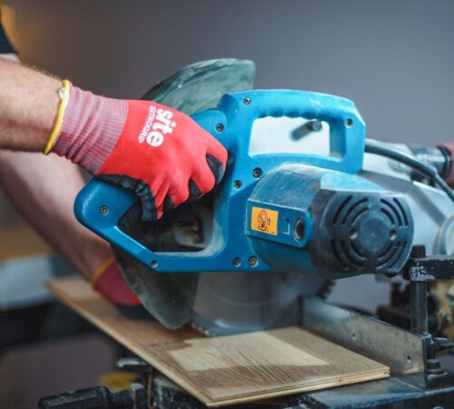 Professional floor layer precisely cutting oak parquet boards with a power saw for a custom installation.