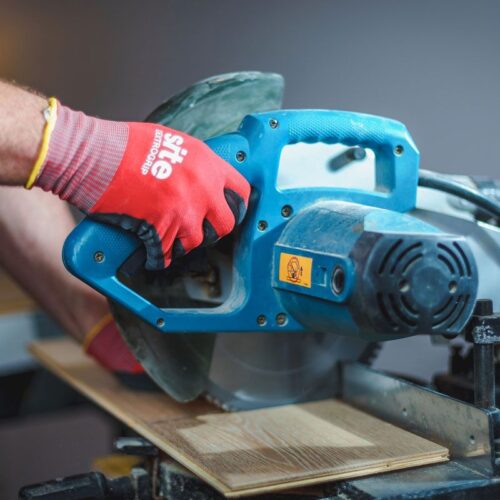 Professional floor layer precisely cutting oak parquet boards with a power saw for a custom installation.