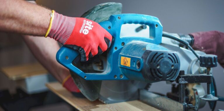 Professional floor layer precisely cutting oak parquet boards with a power saw for a custom installation.