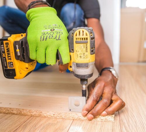 post-three Fixguru furniture assembly expert drilling an IKEA L-bracket into place during a home renovation project.